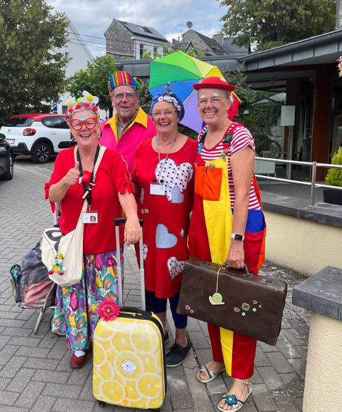 Vier kostümierte Clowns mit gepackten Koffern bereit für ihren Einsatz
