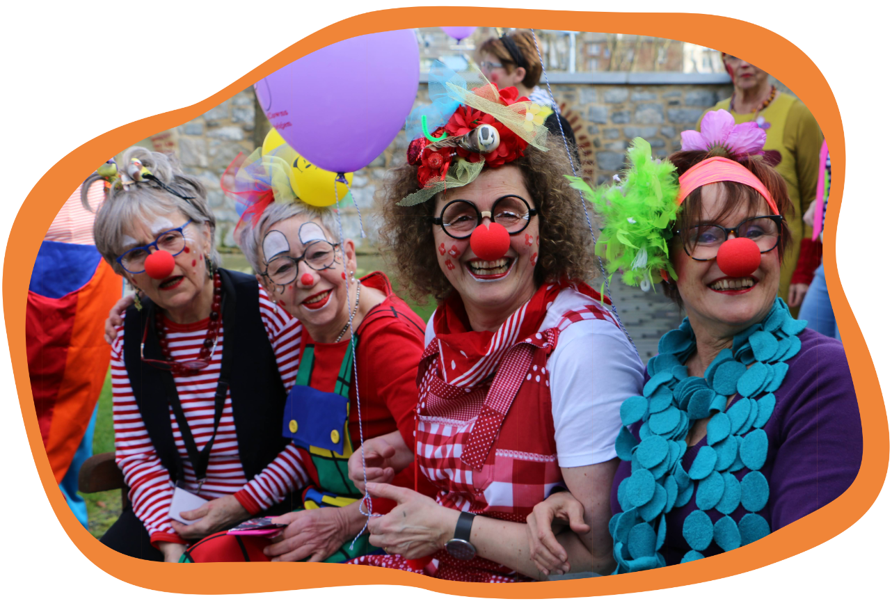 Vier gut gelaunte Clowns mit roten Nasen lächeln in die Kamera
